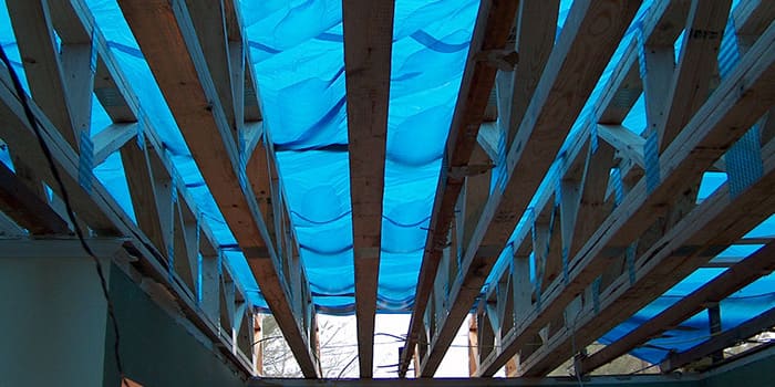 underneath view of roofing beams with tarp over them