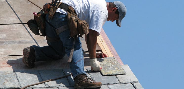 male worker on roof working with shingles