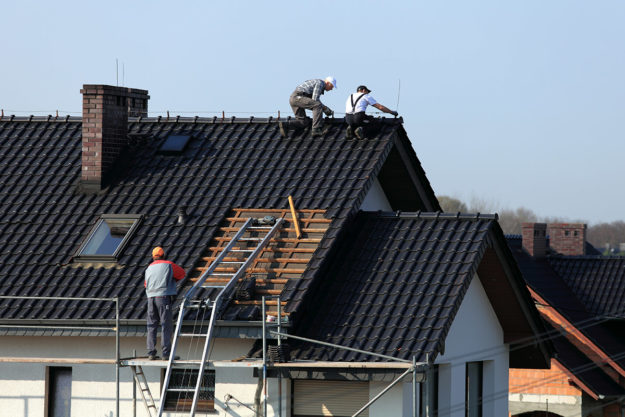 construction workers putting on a new roof showing how to choose a new roof