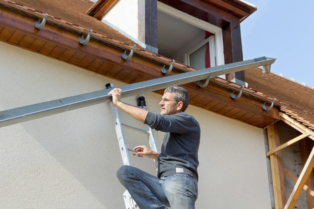 man installing gutters showing what are the best types of gutters