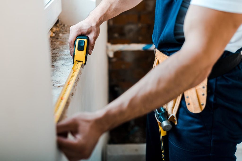 man measures windows for home repair