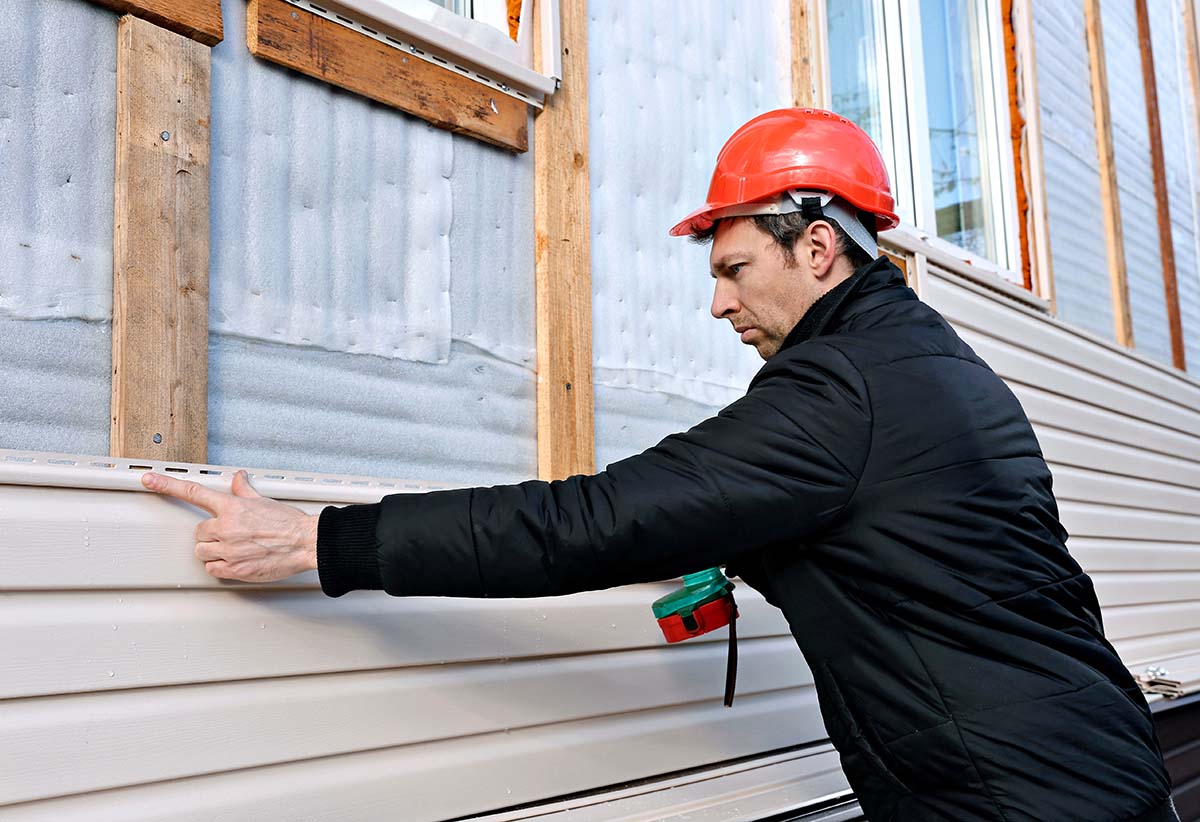 a man repairing a house after learning how to replace vinyl siding
