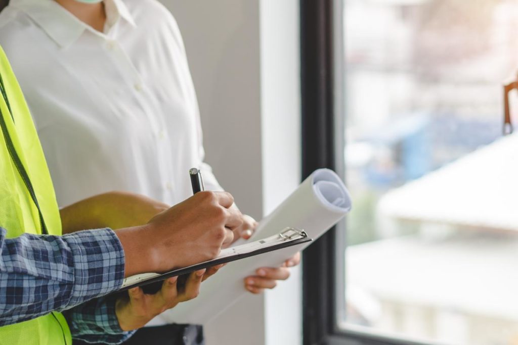 two people hold blueprints discussing home inspection cost