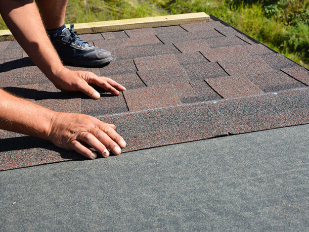 man laying shingles for new residential roof