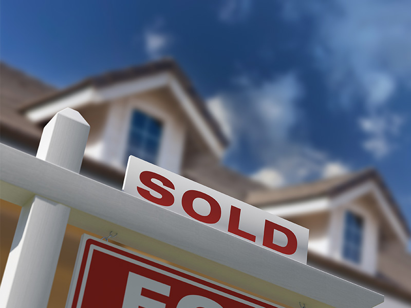 ecroofing-nov-blog2 Closeup of for sale sign with home in background.