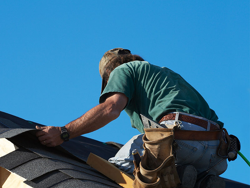 Roofer laying shingles.