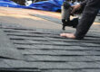 Roofing using a nail gun to secure new shingles to a roof.