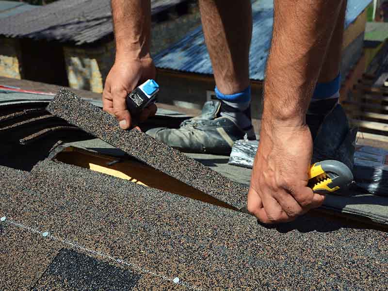 Roofer laying new shingles.