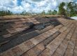 Roof with missing and lifted shingles from wind.