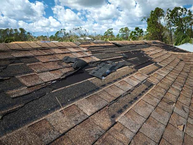 wind-roof-damage Roof with missing and lifted shingles from wind.
