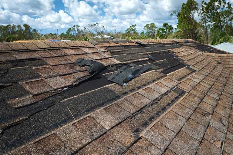 Roof with missing and lifted shingles from wind.